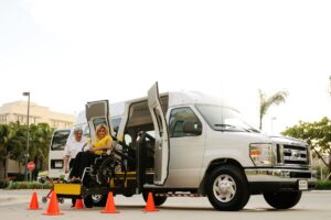 Chauffeur de transport PMR aidant une passagère en fauteuil roulant à embarquer
