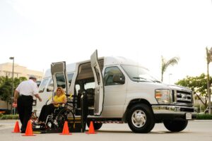 Personne à mobilité réduite montant à bord d'un véhicule adapté avec l'aide d'un chauffeur